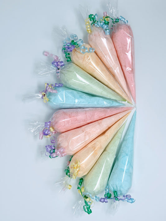 Rainbow of colors of cotton candy in cone shaped bags spread on a table